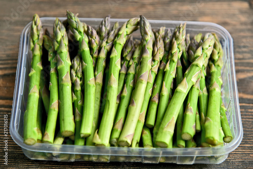 A lot of fresh Green Asparagus (genus) in plastic box on wooden floor