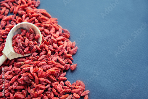 Goji in bowl on wood table. Top view of fresh goji in scoop and bowl. Goji in heart shape on table photo