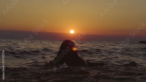 Woman swimming/diving in the sea towards a beautiful sunset photo