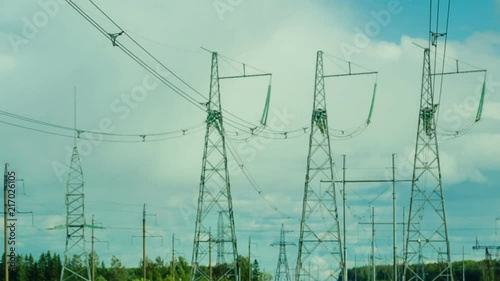 Several power line supports are in the background of moving clouds. photo