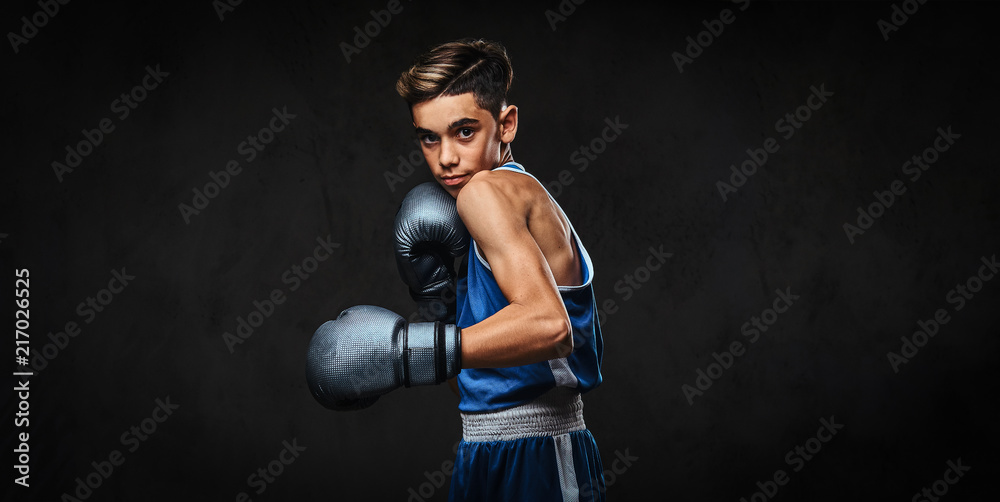 Handsome young boxer during boxing exercises, focused on process. Isolated on the dark background.