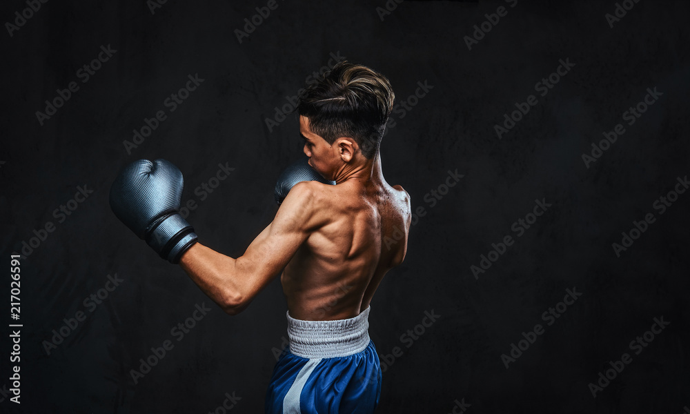 Handsome shirtless young boxer during boxing exercises, focused on process with serious concentrated facial.