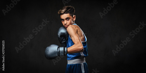 Handsome young boxer during boxing exercises, focused on process. Isolated on the dark background. © Fxquadro