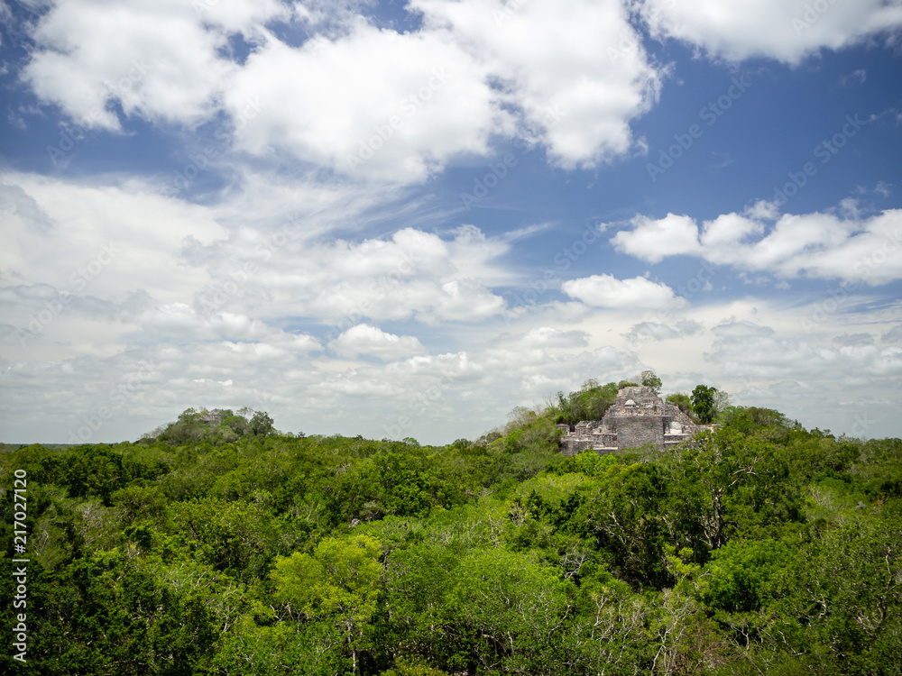 Two ancient Mayan stone structures rising out of the jungle canopy at Calakmul, Mexico