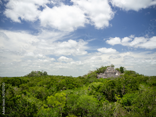 Two ancient Mayan stone structures rising out of the jungle canopy at Calakmul, Mexico