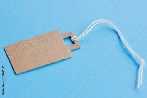 Blank brown cardboard price tag, sale tag, gift tag, address label on blue background