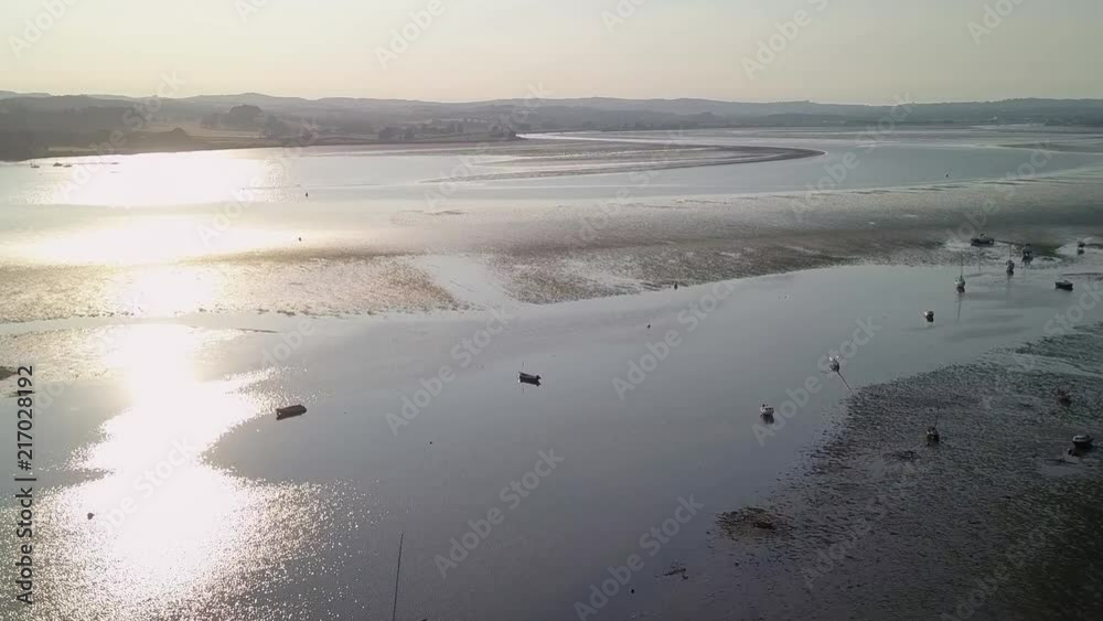 Flying over docked sailing boats off of the shore of Lympstone beach in East Devon England. This coastal town is a prominent tourist location. It has nature, beaches, and much more to do. Flying over docked sailing boats off of the shore of Lympstone beach in East Devon England. This coastal town is a prominent tourist location. It has nature, beaches, and much more to do.