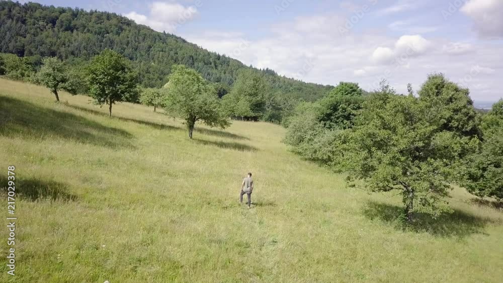 A young man is walking over a field in slow motion. His facial expression looks very thoughtful. A young man is walking over a field in slow motion. His facial expression looks very thoughtful.