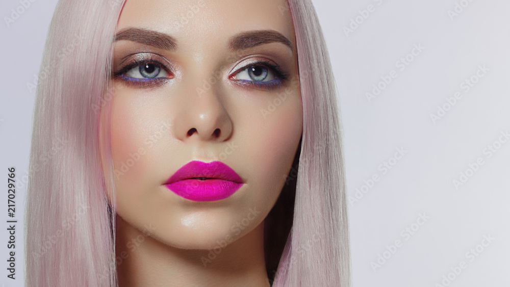 Close-up of woman's lips with fashion bright pink make-up. Beautiful female  mouth, full lips with perfect makeup. Part of female face. Choice lipstick.  Pink wavy hair of a Barbie doll Stock Photo