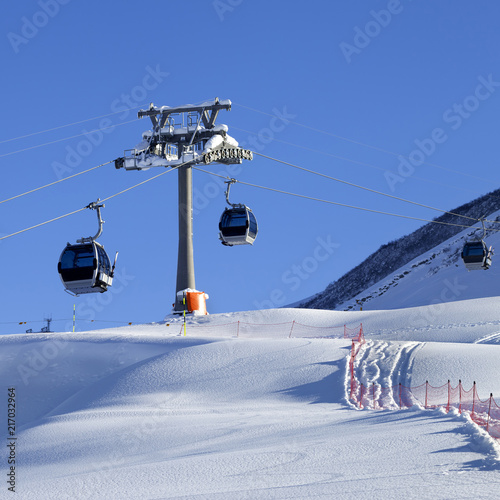 Gondola lift and off-piste slope with new-fallen snow on ski resort at sun evening