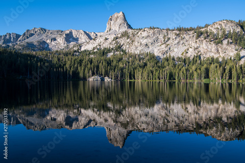 Reflection of a granite mountain crag and cliffs under a perfect blue sky in a calm lake - Crystal Crag and Lake George in the Mammoth Lakes area of California s eastern Sierra mountains