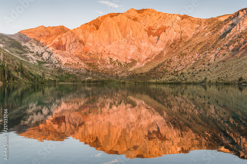 Sunrise casts golden light on mountain peaks reflected in the calm waters of Convict Lake in the eastern Sierra Nevada mountains of California