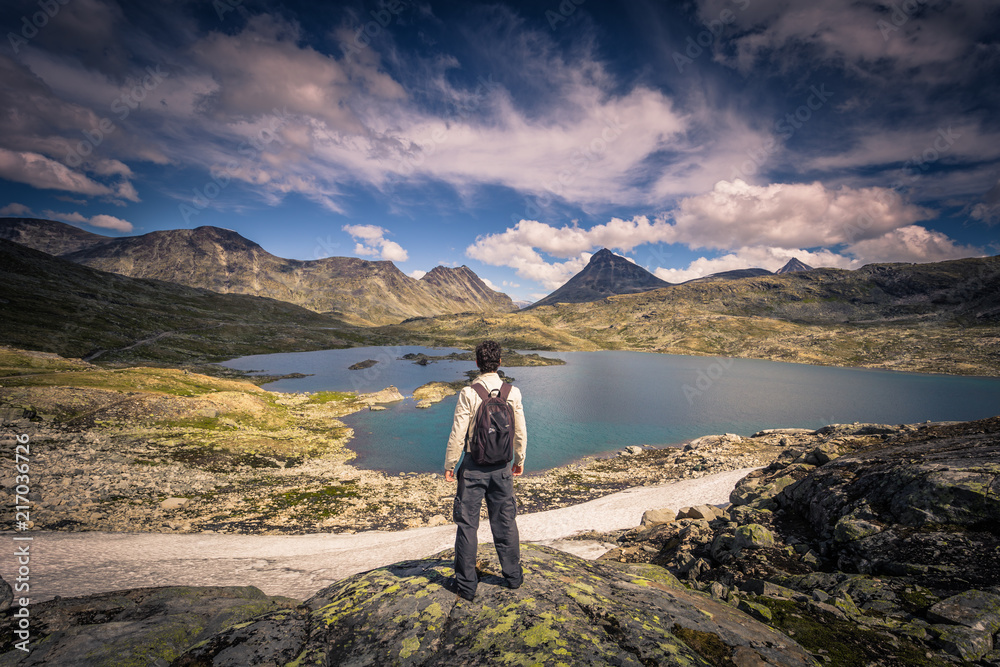 Fototapeta premium Jotunheimen National Park - July 29, 2018: Traveler in the wild mountain landscape in the Jotunheimen National Park, Norway