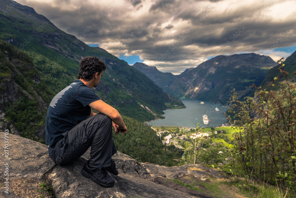 Geiranger - July 30, 2018: Traveler at Flydalsjuvet viewpoint looking down at the stunning UNESCO Geiranger fjord, Norway