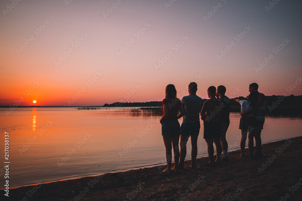 Silhouette of friends at the beach looking on the sunset in the summer ...