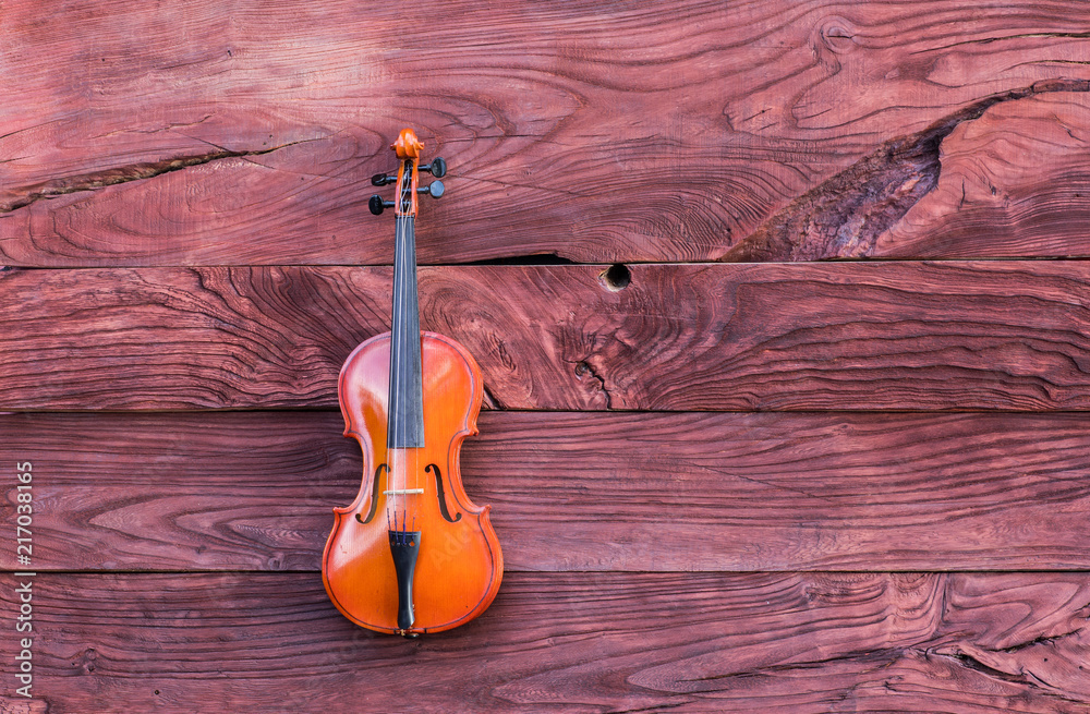 Naklejka premium violin on a red wooden background