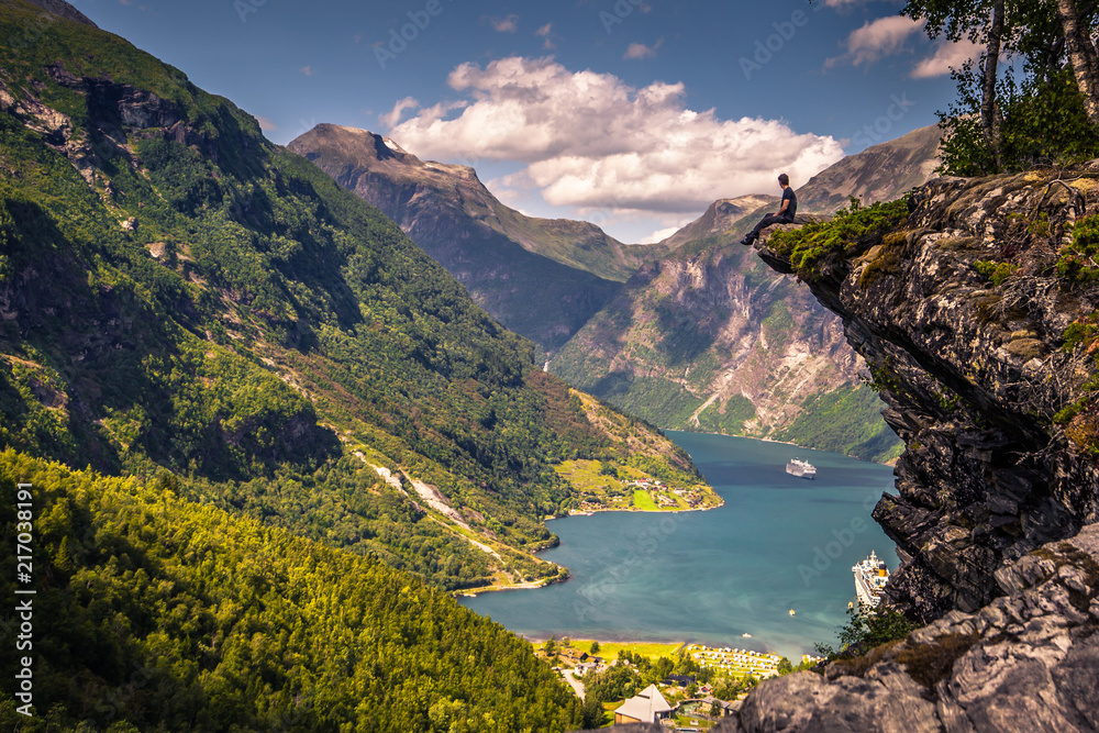 Geiranger - July 30, 2018: Traveler at Flydalsjuvet viewpoint looking down at the stunning UNESCO Geiranger fjord, Norway