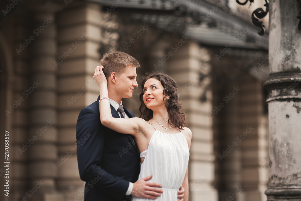Beautiful wedding couple, bride, groom kissing and hugging against the background of theater