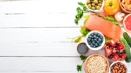 A set of healthy food. Fish, nuts, protein, berries, vegetables and fruits. On a white background. Top view. Free space for text.