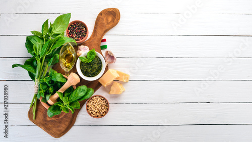 Traditional basil pesto sauce. Basil, parmesan cheese, olive oil. Top view. On a white wooden background. Free space for text.