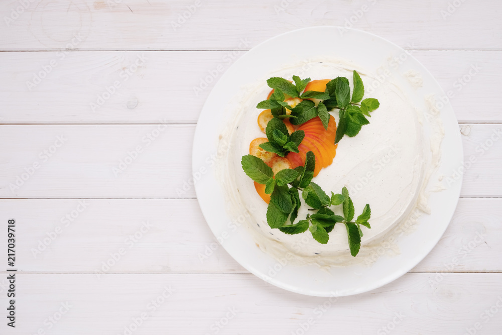 Tasty homemade cream cheese cake with fresh fruits and blueberries and mint on white plate on light wood background top view with copy space for text Tasty homemade cream cheese cake with fresh fruits and blueberries and mint on white plate on light wood background top view with copy space for text