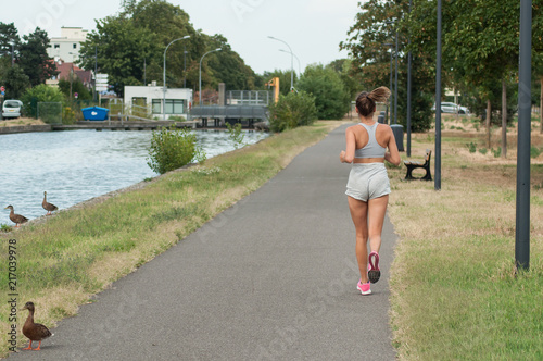 portrait on back view of sexy girl running in border channel