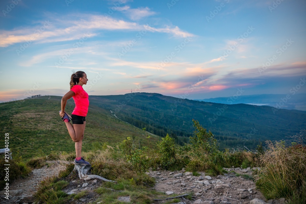 Woman stretching after trail running in mountains.