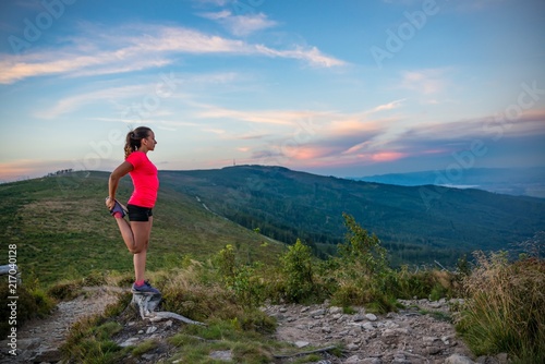 Woman stretching after trail running in mountains.