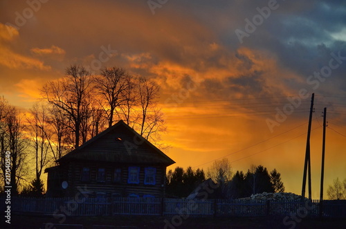  A bright scarlet sunset against the background of a wooden house