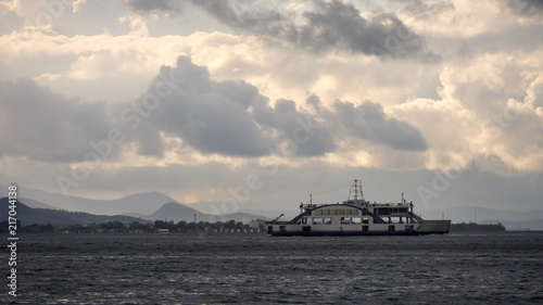 A ferry boat is navigating in the sea in front of the turkish city of Izmir, Turkey, during the fluffy cloudy sky © ersoy