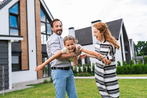 Wonderful mood. Nice cheerful girl smiling while having fun together with her parents