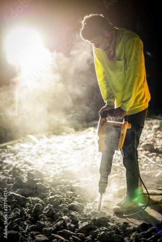 Worker repairing works with jackhammer at night