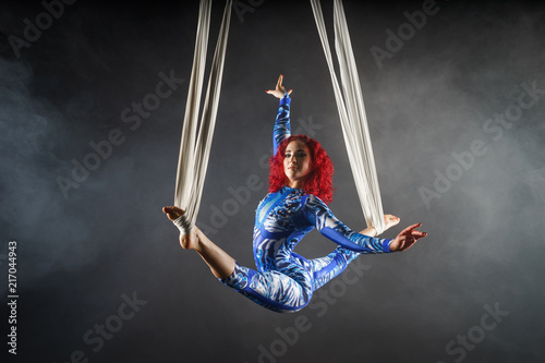 athletic sexy aerial circus artist with redhead in blue costume dancing in the air with balance photo