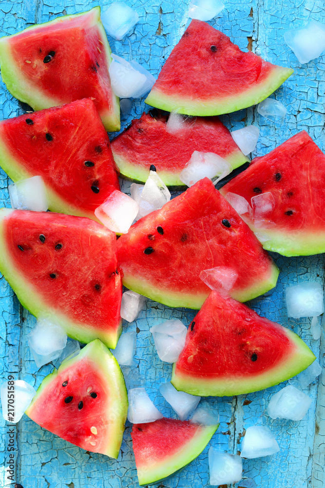 Watermelon slices with slices of ice on a blue background