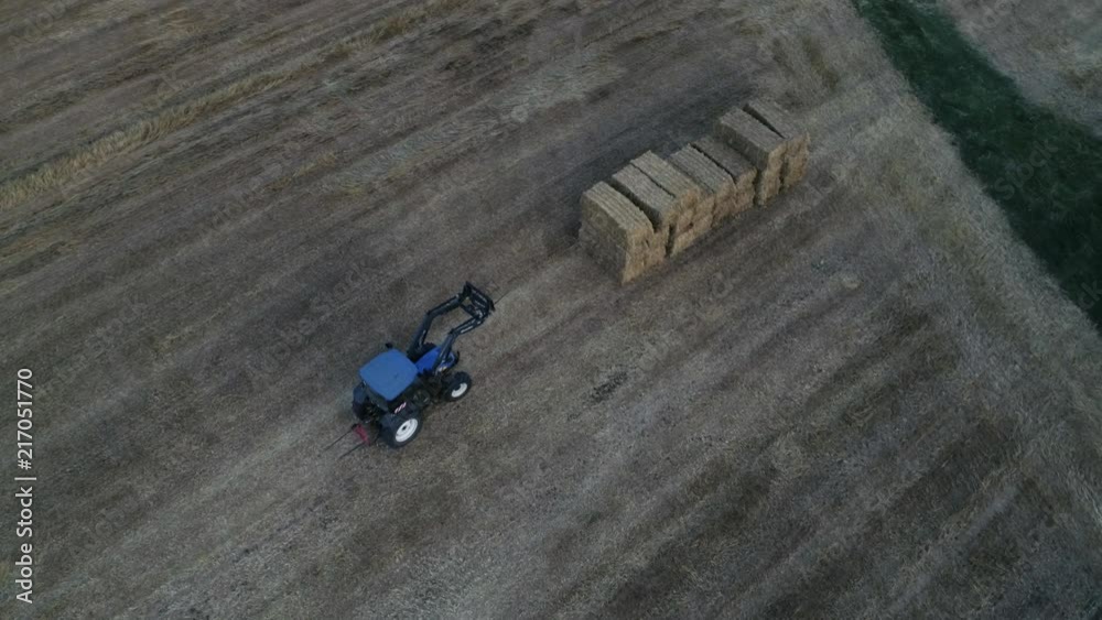 blue tractor moving hay stacks strawballs around aerial shot overview blue tractor moving hay stacks strawballs around aerial shot overview