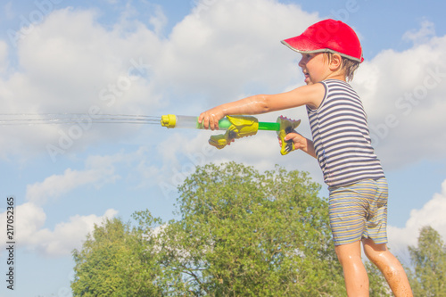 Child with a water pistol. The boy shoots water from a water pistol.