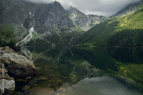 Beautiful view of green forest, hills and rocky mountains with reflection on the Morskie Oko lake, High Tatras, Zakopane, Poland. Foggy day