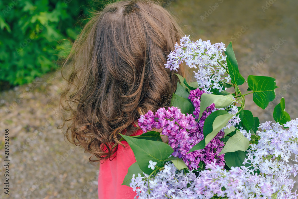 Fototapeta premium girl child holding a bouquet of lilac. 