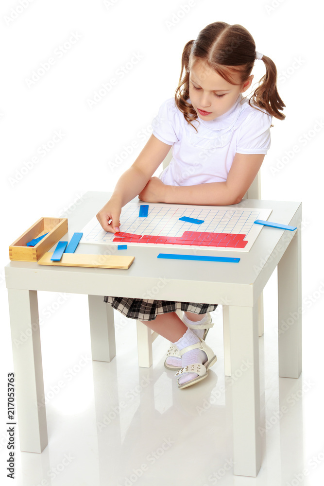 A little girl is studying Montessori stuff.