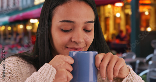 Smiling Hispanic girl enjoys a cup of coffee at a cafe in Bruges 