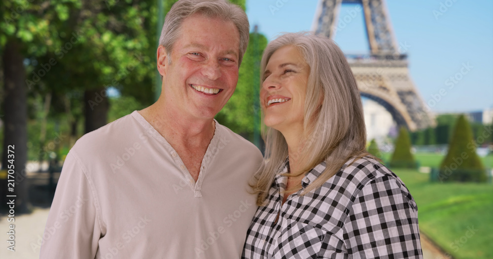 Senior Caucasian couple stand together in front of Eiffel Tower