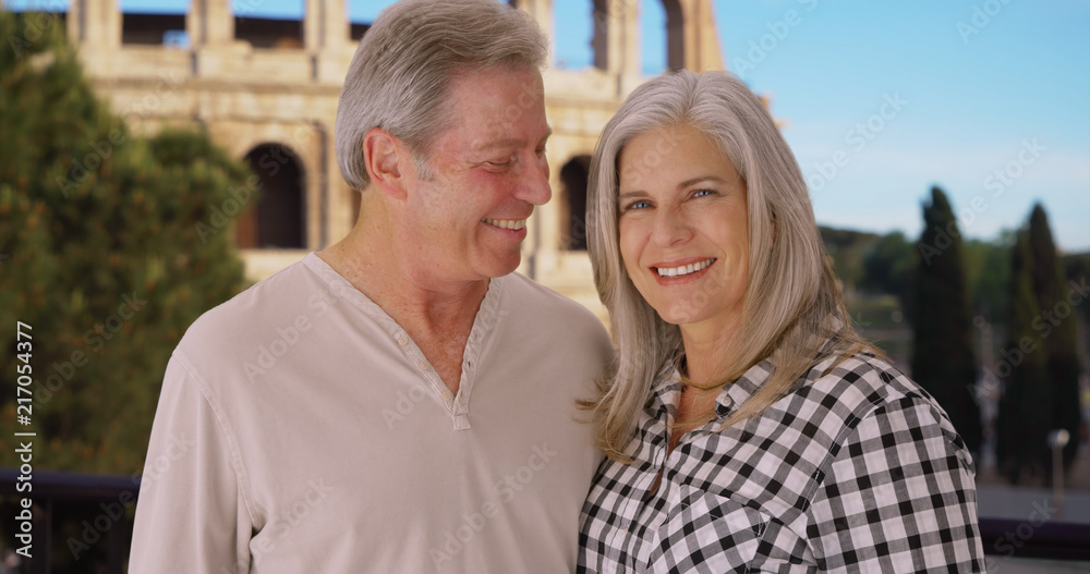 Happy mature Caucasian couple smile happily in front of Colosseum in Rome Happy mature Caucasian couple smile happily in front of Colosseum in Rome