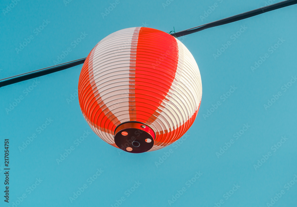 Obraz premium Paper red-white japanese lanterns Chochin hanging on blue sky background