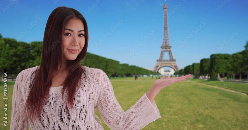 Cute Japanese female holding hand out to show Eiffel Tower