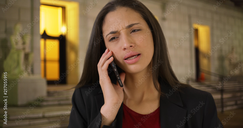 Serious Latina female talks to business colleague on mobile device Serious Latina female talks to business colleague on mobile device