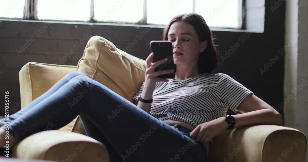 Millennial using smartphone in a loft apartment Millennial using smartphone in a loft apartment