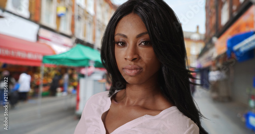 African-American female looks slyly at camera near street market in Brixton photo