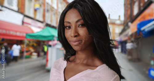 African-American female smiling at camera near street market in Brixton © rocketclips
