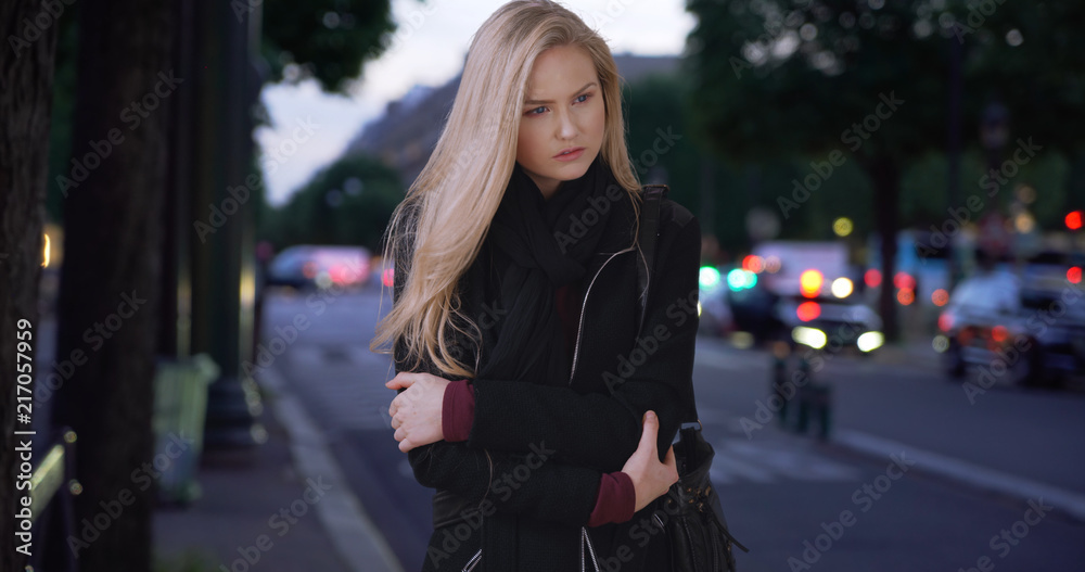 Stunning modern white woman poses for camera while standing on sidewalk