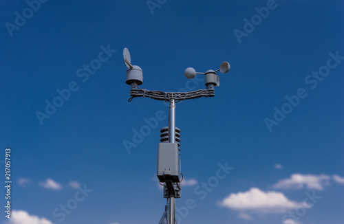 Home weather station on a background of blue sky with the sun behind the clouds. Measurement of temperature, humidity and wind direction